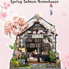 A detailed miniature Japanese tea house diorama featuring a traditional wooden structure, pink blossoms, and mossy landscapin
