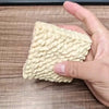 A hand holds a white, textured squishy toy shaped like a dog noodle for stress relief.
