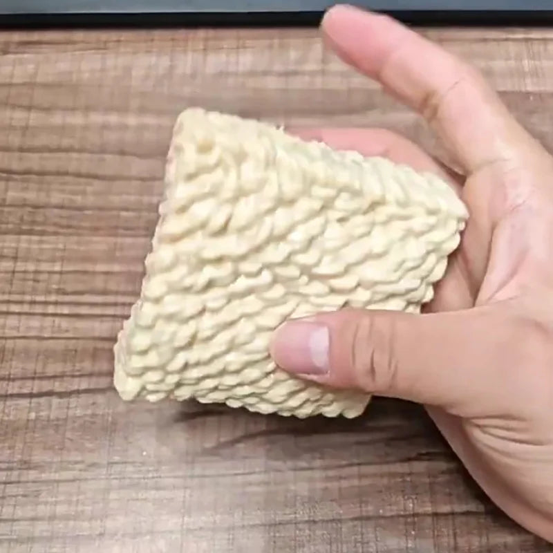 A hand holds a white, textured squishy toy shaped like a dog noodle for stress relief.