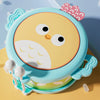 A light blue owl-shaped musical drum for kids with pink accents resting on a yellow surface.