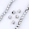 Silver faceted crystal beads in various sizes and shapes arranged diagonally on a white background