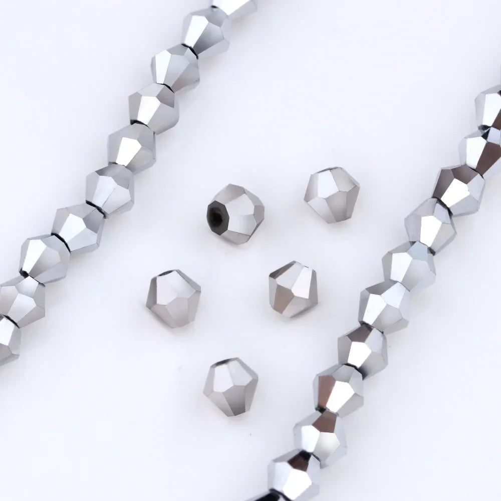 Silver faceted crystal beads in various sizes and shapes arranged diagonally on a white background