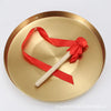 A polished brass gong with a wooden mallet is displayed on a round metal plate.
