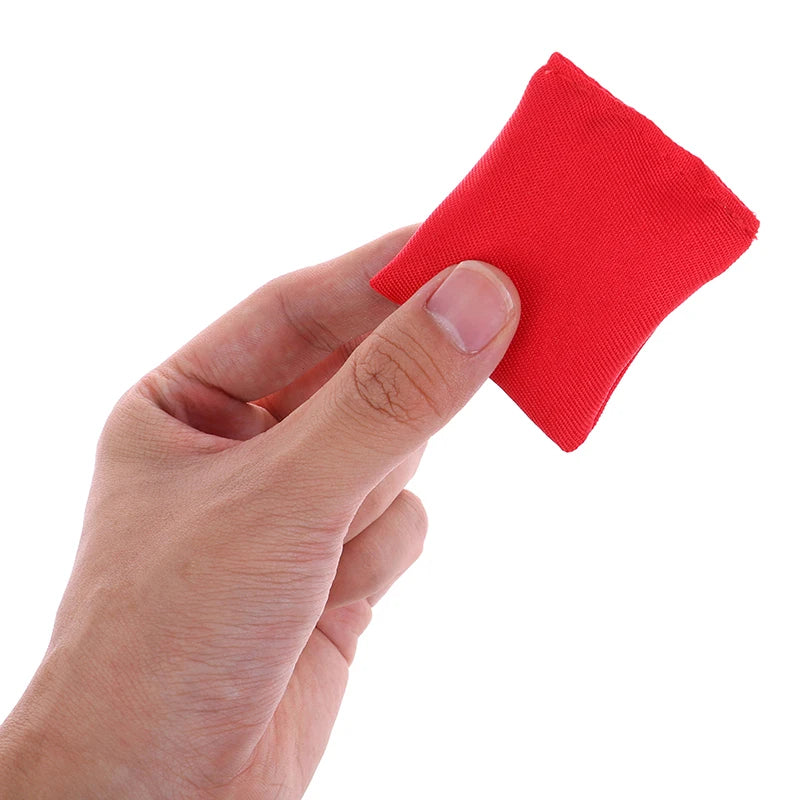 A hand is holding a bright red mini bean bag for kids.