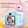 A pink digital camera is shown next to a light blue camera displaying a child's face.