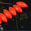 A row of bright orange oval fishing floats with attached bobber beads is displayed on a dark surface.