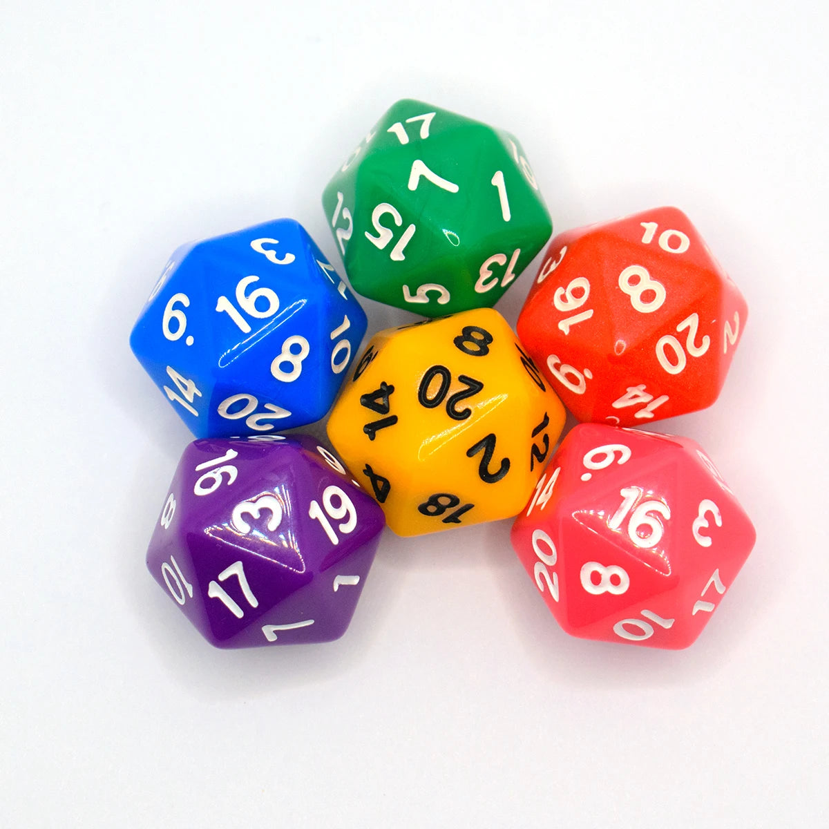 A collection of six polyhedral dice in various colors including green blue red and purple resting on a white surface.