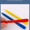 A hand holds several plastic crayons in red, blue, and yellow colors on a white background.