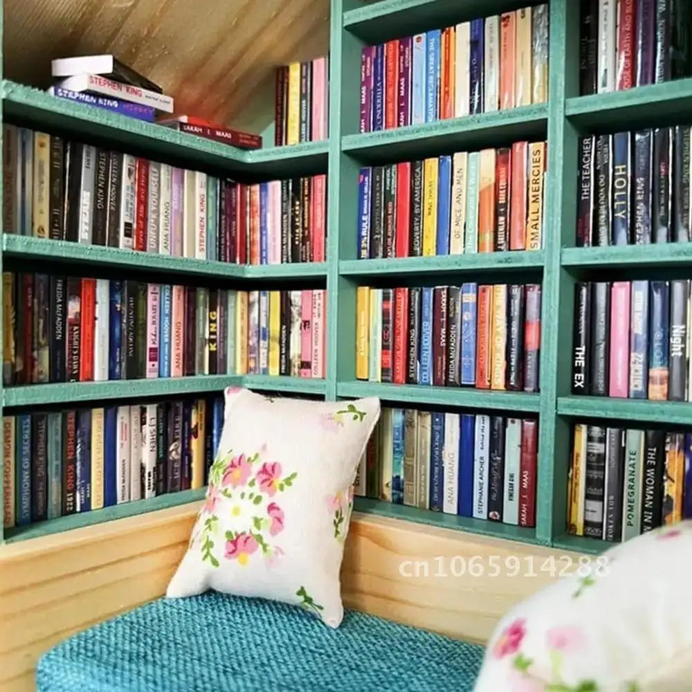 A wooden bookshelf filled with miniature books and decorated with a pink floral pillow.