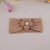 A beige floral elastic baby headband with a white center flower, displayed on a light background.