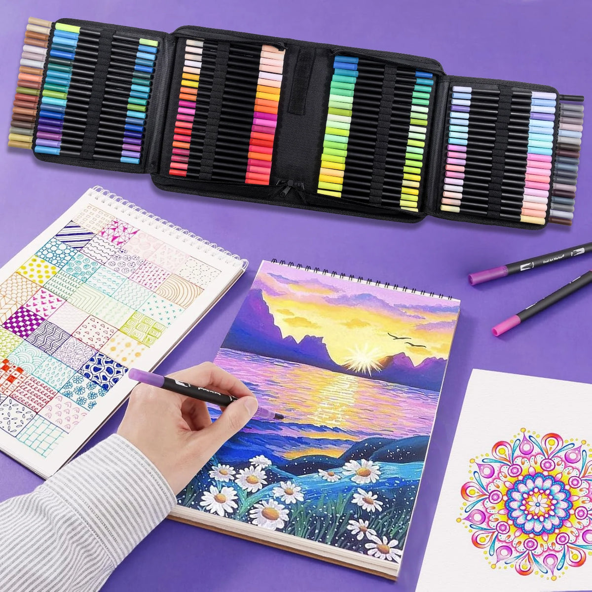 A black dual-tip art marker set is shown next to a sketchbook with colorful watercolor illustrations.