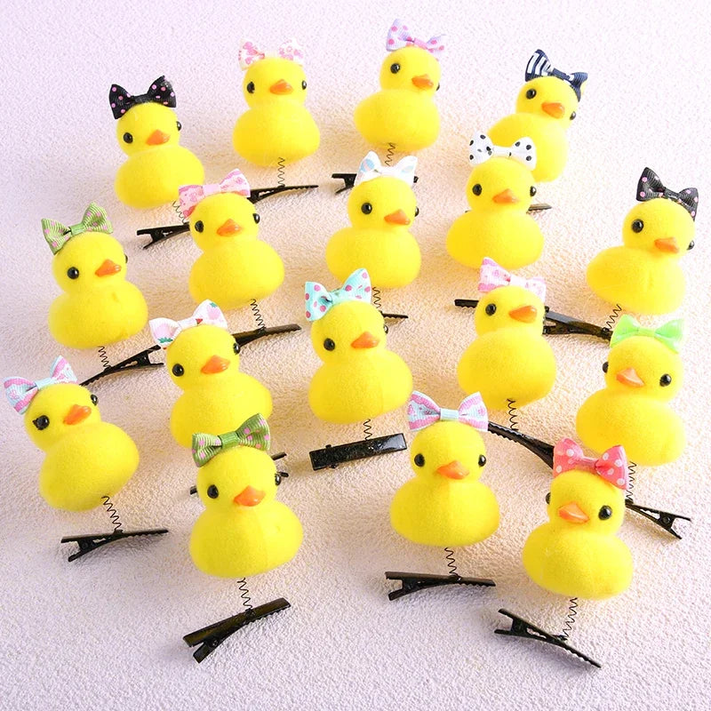 A collection of yellow duck plush hair clips with various bows and accessories arranged on a white surface.