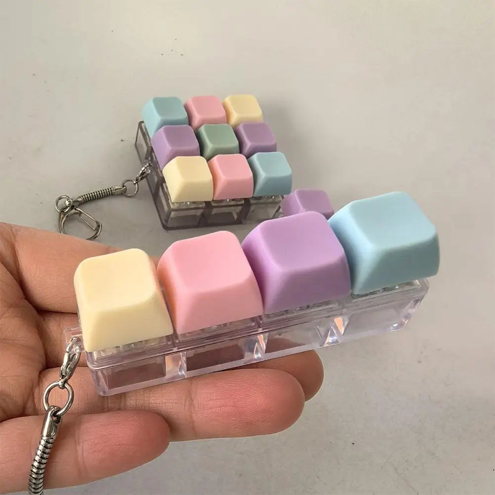 A hand holds a clear plastic container filled with pastel colored keyboard fidget toys for stress relief.