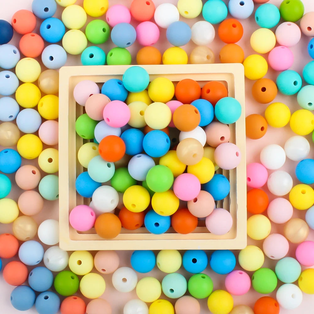 A wooden tray filled with a colorful mix of round silicone beads in various sizes and colors for DIY jewelry making