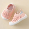 A pair of light pink breathable mesh slip-on sneakers for toddlers with white soles and gray accents.