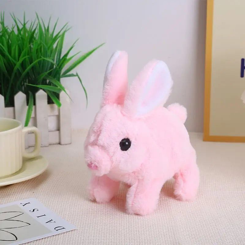 A pink rabbit plush toy with long ears is displayed on a white surface next to a potted plant.
