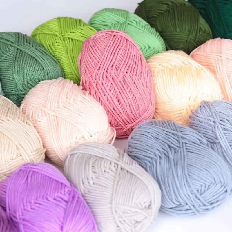 A collection of pre-dyed milk cotton yarn in various shades of green, pink, yellow, and purple.