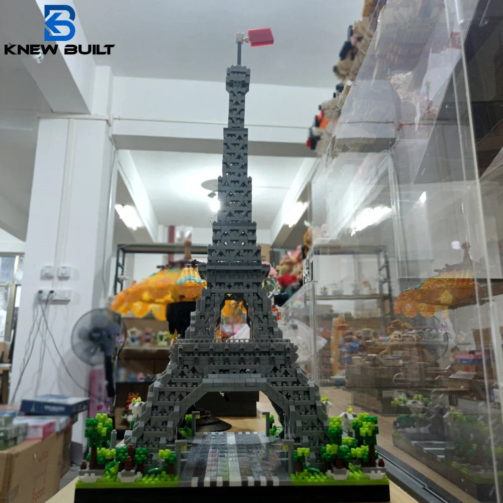 A detailed miniature model of the Eiffel Tower built from gray building blocks displayed in a glass case.