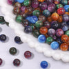 A close-up view of a large pile of vibrant tiger eye resin beads in various colors, including green, purple, blue, and orange