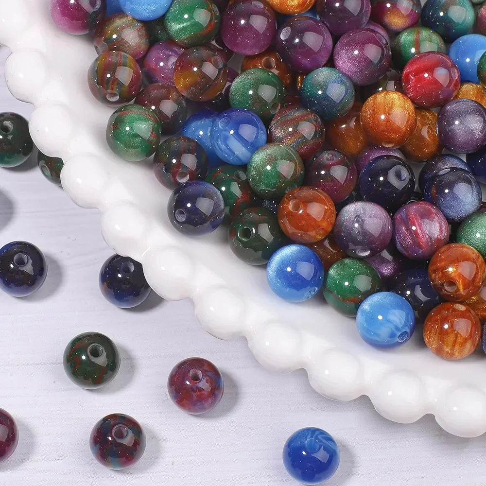 A close-up view of a large pile of vibrant tiger eye resin beads in various colors, including green, purple, blue, and orange