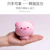 A hand is holding a pink squishy pig stress relief toy.