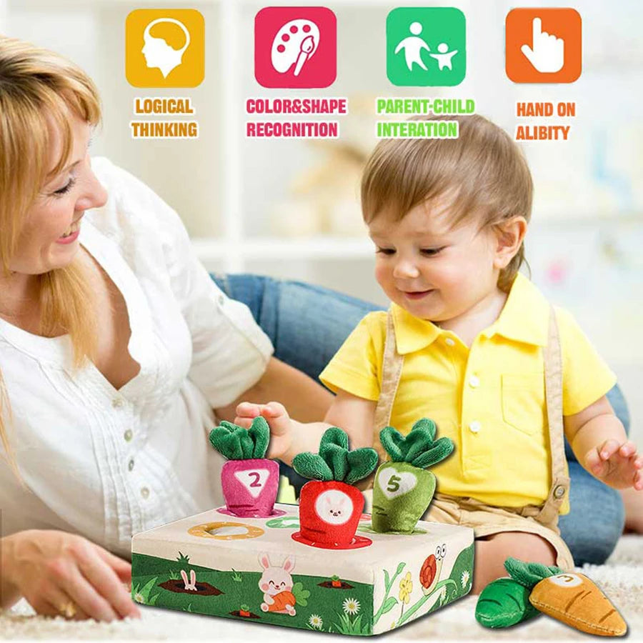 A toddler plays with a soft, washable carrot pull toy for sensory learning alongside a mother.