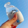 A hand holds a clear bottle labeled Chiboki drink cup toy against a blue sky background.