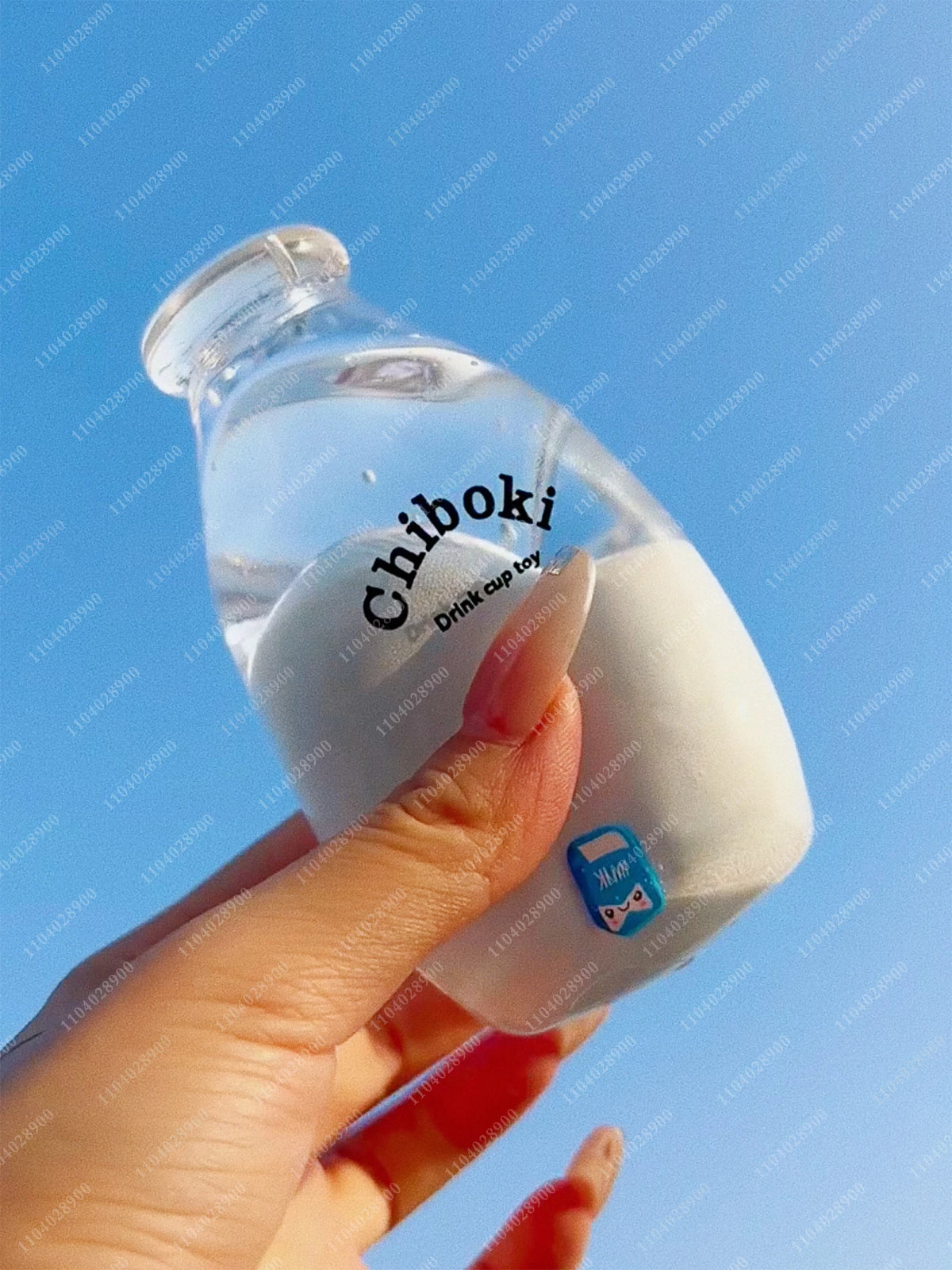 A hand holds a clear bottle labeled Chiboki drink cup toy against a blue sky background.