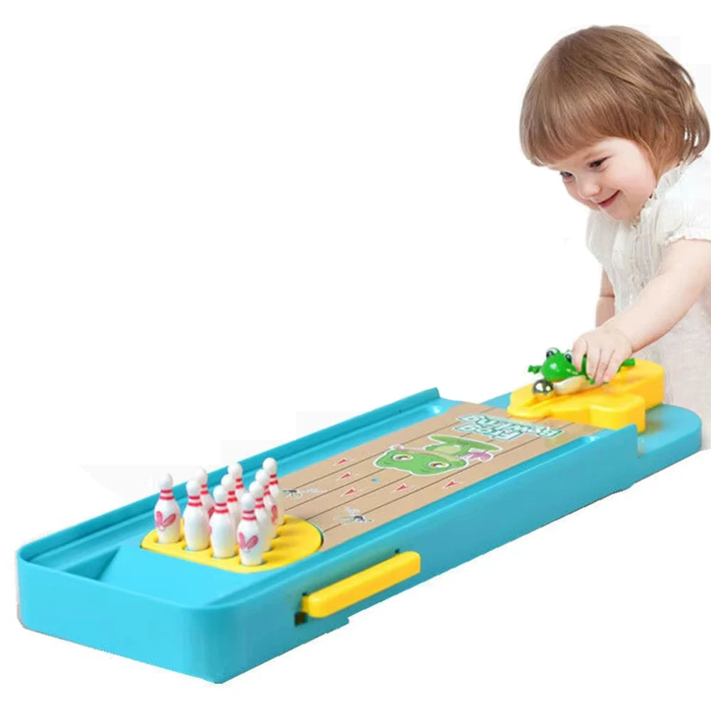 A young child is playing a mini frog bowling game set with colorful pins on a wooden track.