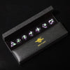 A set of six purple resin polyhedral dice displayed inside a dark gray box with a gold mini planet emblem.