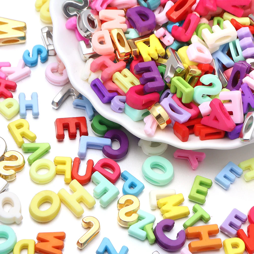 A pile of mixed colored acrylic letter beads in various shapes and sizes for DIY crafts