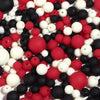 A close-up view of various matte acrylic beads in black, white, and red colors scattered on a white surface.
