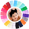 A colorful arrangement of nylon knit bow headbands for baby girls in various shades of pink, red, blue, green, and purple.