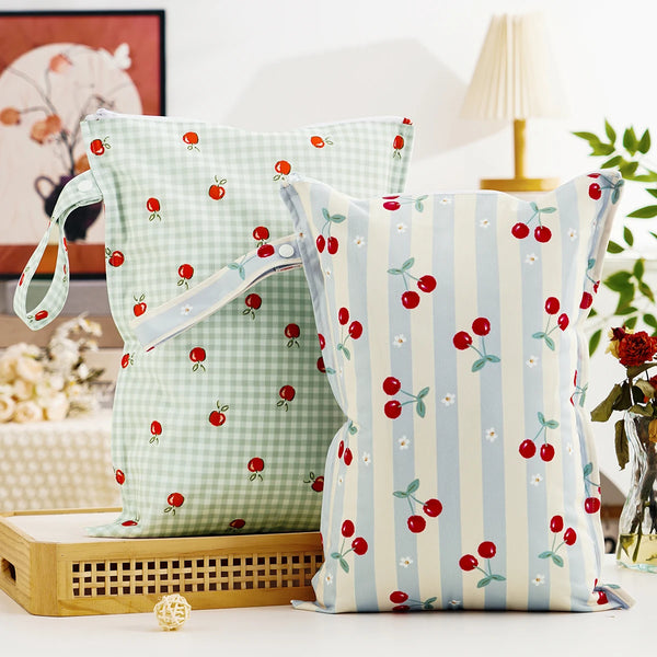 A light green patterned reusable zippered diaper cover and wet bag with red and white accents.