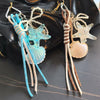 A set of beaded keychain charms featuring sea creatures and shells on a dark leather background.