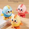Three colorful clockwork animal toys of chicks in blue, pink, and yellow sitting on a wooden surface.