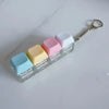 A clear plastic keychain organizer filled with colorful fidget cubes, including white, pink, yellow, and light blue.
