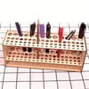 A wooden organizer holds various art brushes and pencils in individual slots for storage.