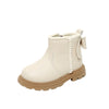 A pair of light beige faux leather winter boots for kids with a fluffy trim and a small decorative detail.