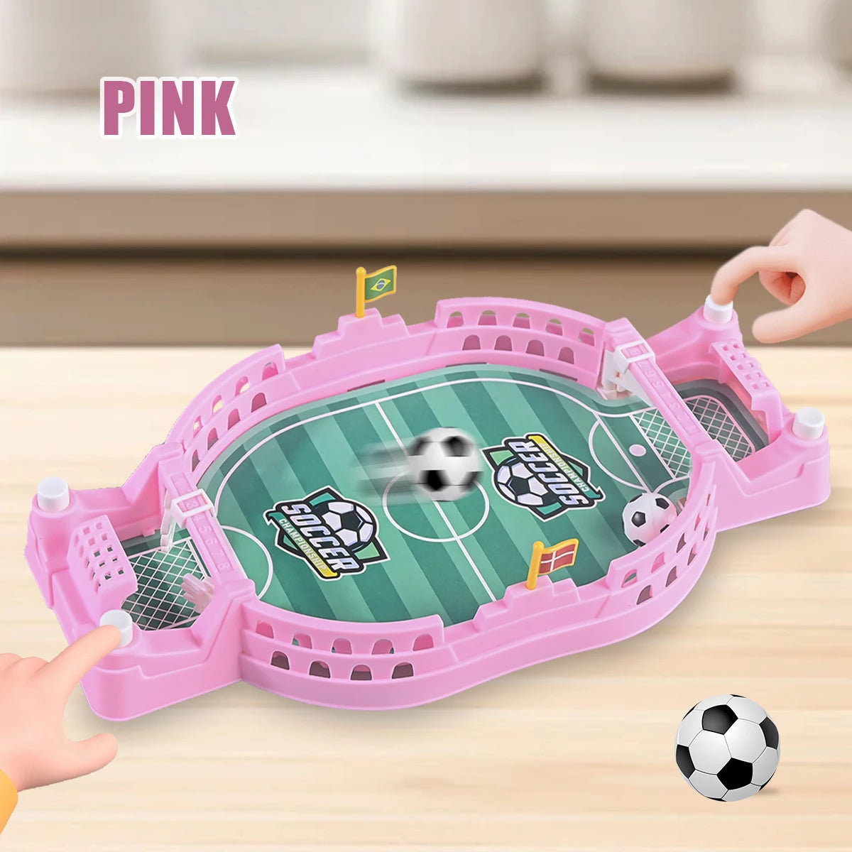 A pink tabletop foosball game is shown with a soccer ball and goal nets on a wooden surface.