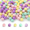A pile of round, flexible silicone beads in various pastel colors including pink, yellow, purple, and green.