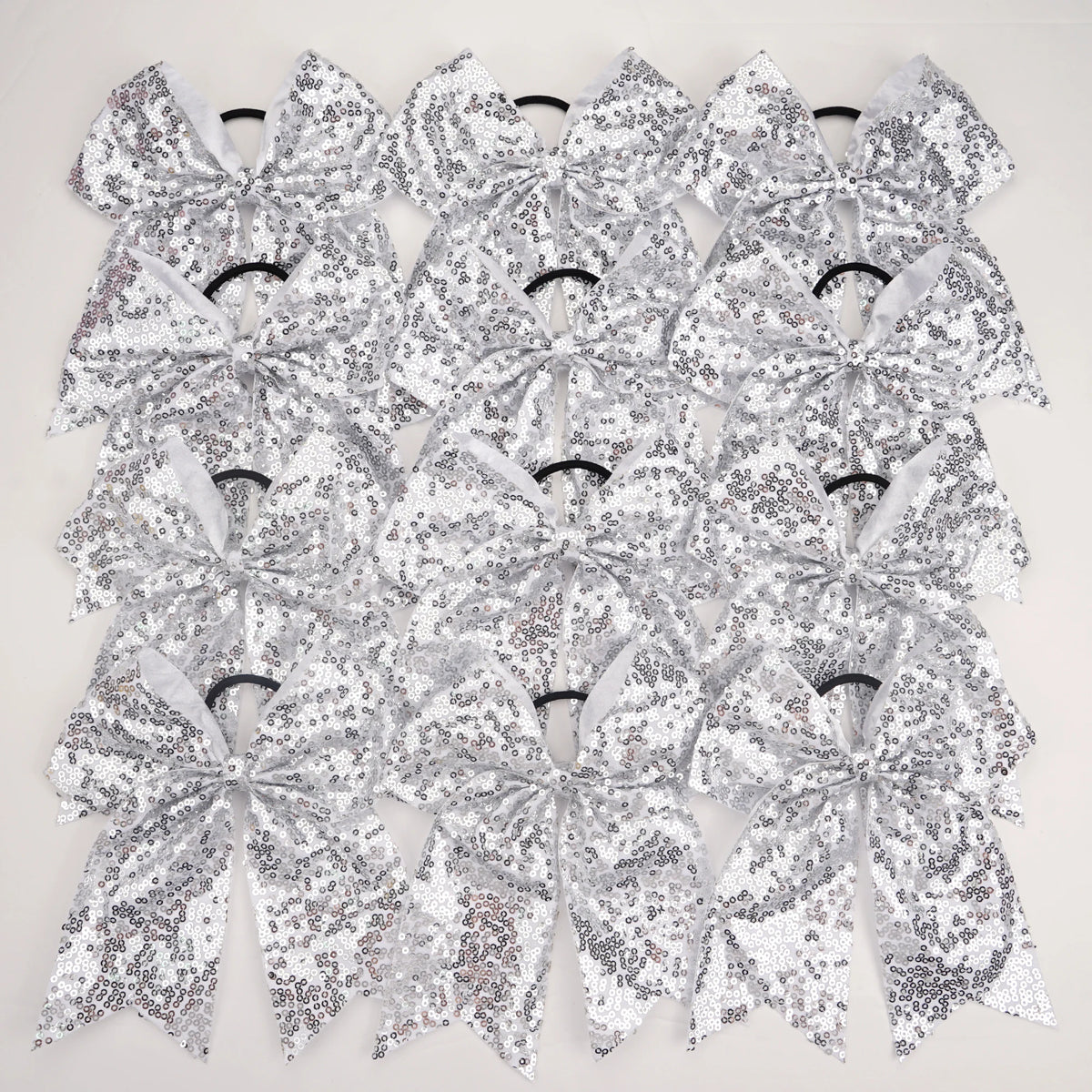 A pack of twelve silver glitter sequin pigtail bows for girls, featuring elastic hair ties.