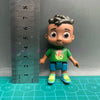 A playful cartoon PVC figurine of a boy with dark skin and curly hair wearing a green shirt and blue shorts.