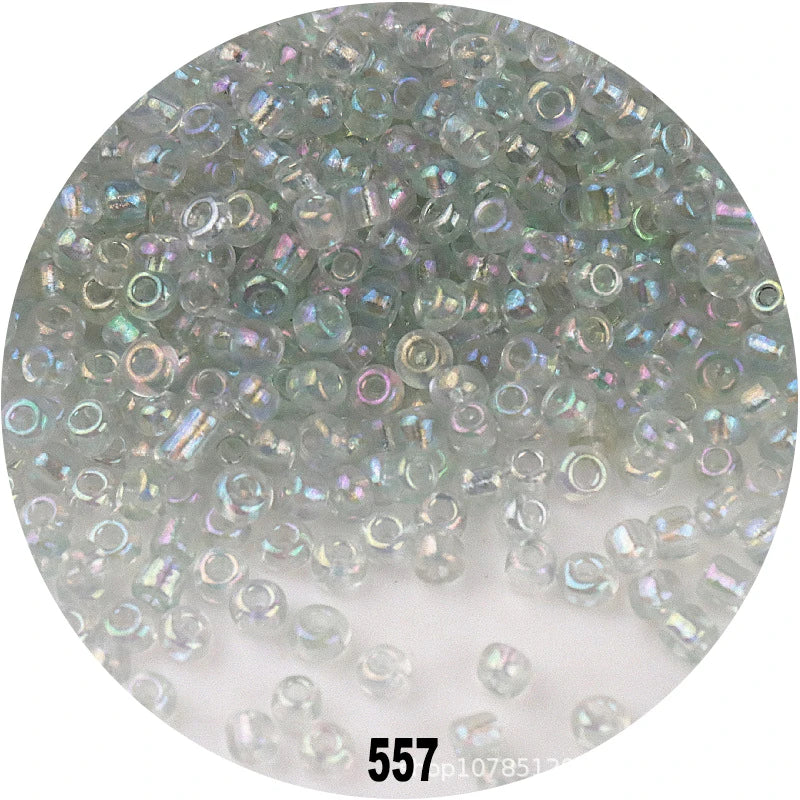 A close-up view of numerous colorful round loose glass seed beads scattered on a white surface.