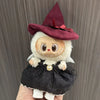 A doll dressed as a Halloween pumpkin with a maroon witch hat and black dress.