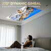 A 270° dynamic gimbal projector is mounted on a ceiling, displaying a panoramic view of a city and ocean in a bedroom setting