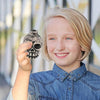 A smiling child holds up a ceramic Aztec skull whistle for the camera.