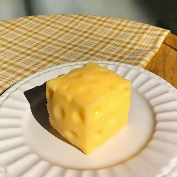 A yellow cheese squeeze stress relief toy resting on a white plate with a yellow checkered napkin.