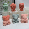 A collection of pink and green 3D bear hug silicone candle molds in various textures and shades.