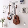 A white wall features a guitar wall hook displaying various musical instruments including an electric guitar and an acoustic 
